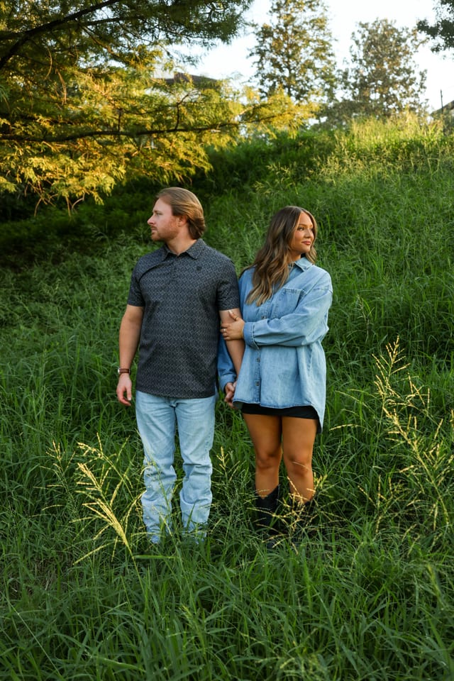 Couple holding hands in a sunlit field of tall grass