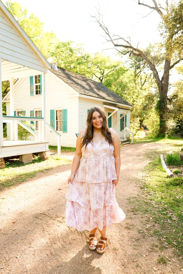 Pink floral tiered dress in front of a farmhouse