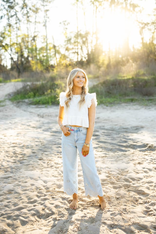 Senior in a white top on a sandy beach at sunset