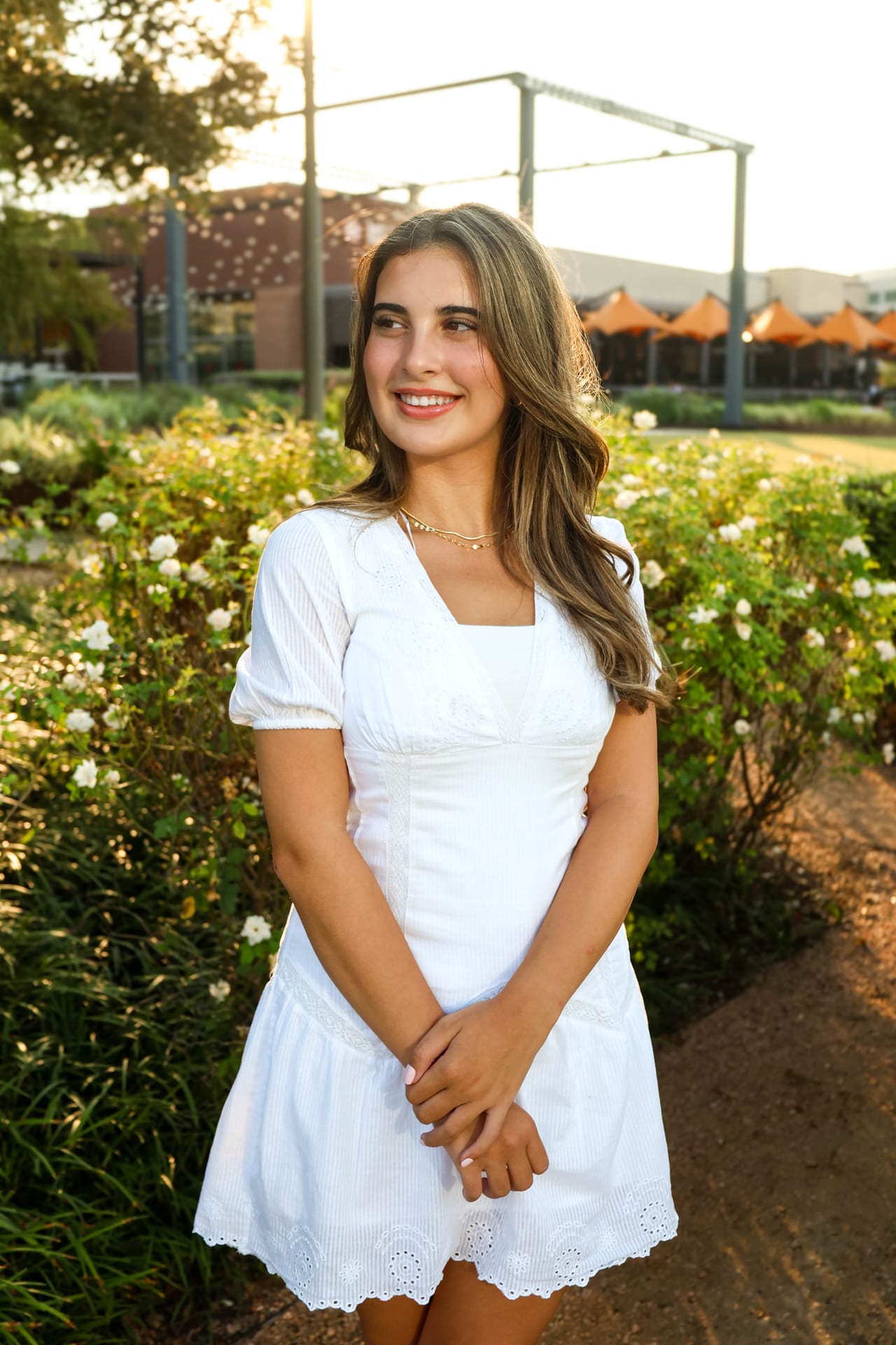 Senior in white square-neck dress in a sunlit garden