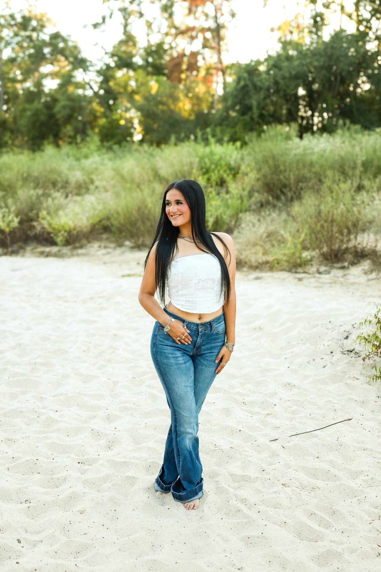 Senior in white tube top and jeans on a sandy path