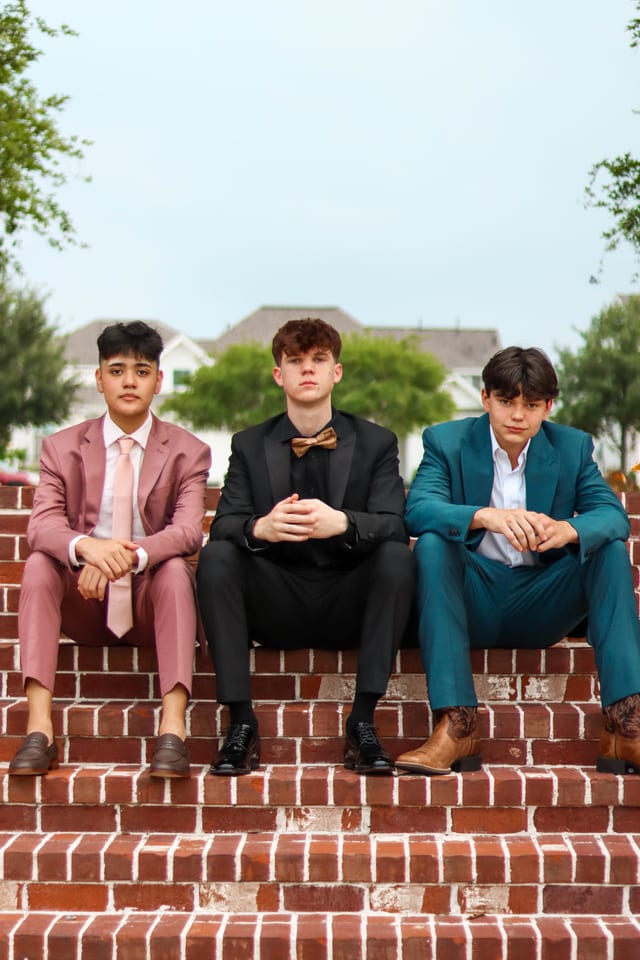Three boys in colorful suits on brick steps