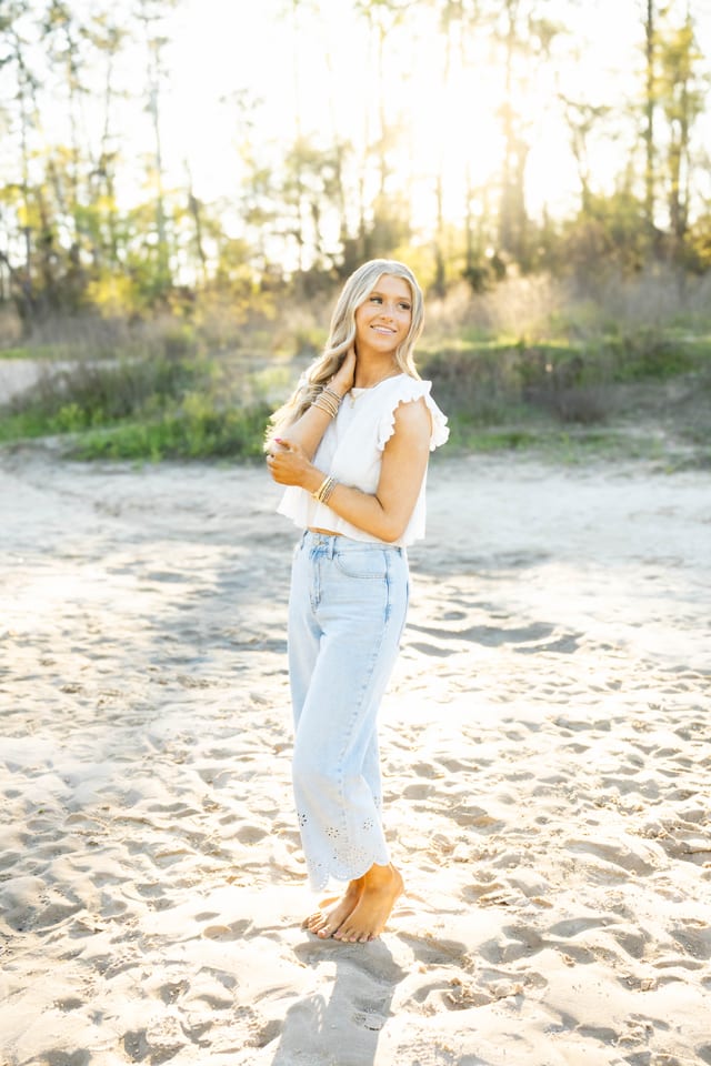 Senior in a white top on a sunlit sandy beach