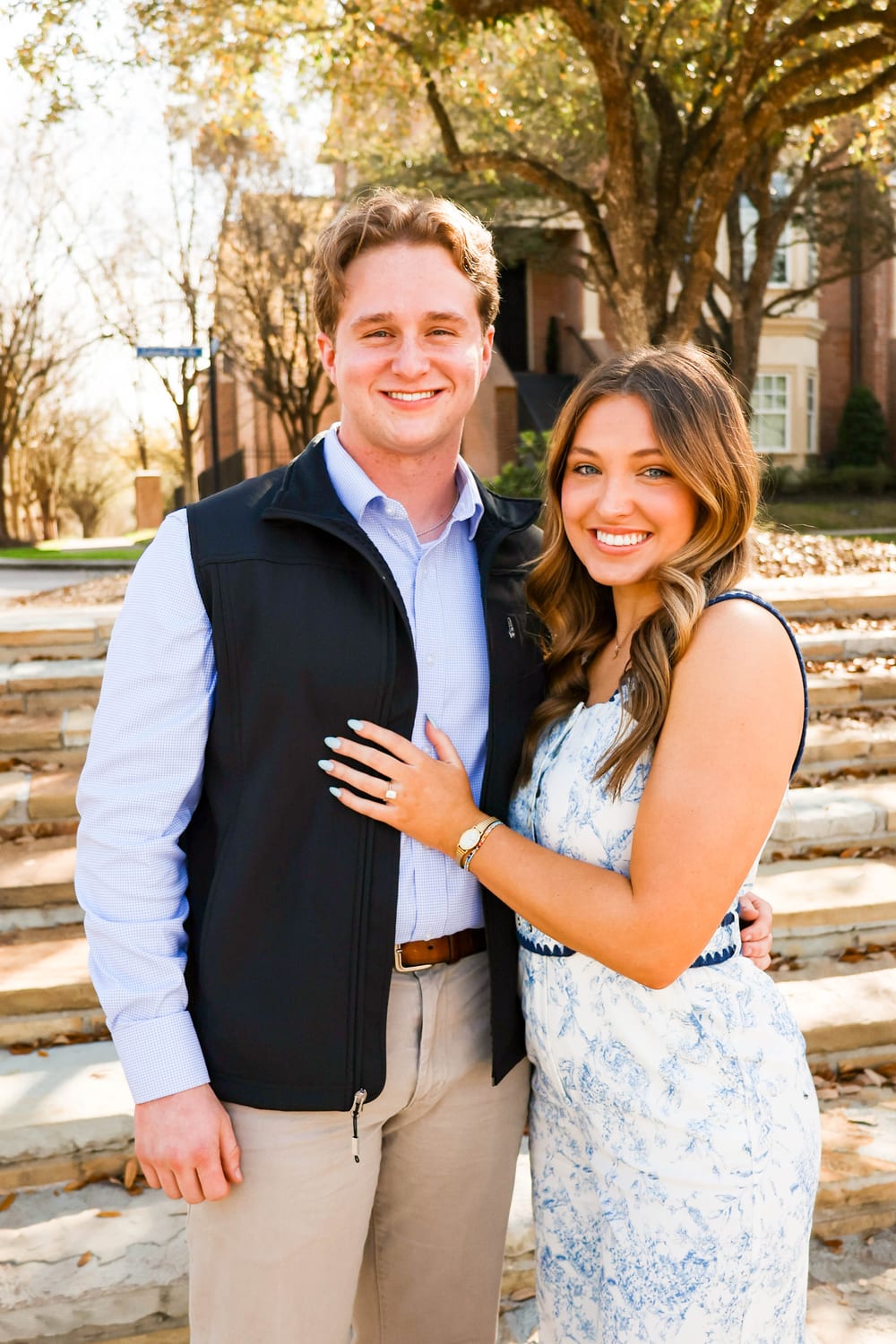 Engaged couple on stairs, showing ring