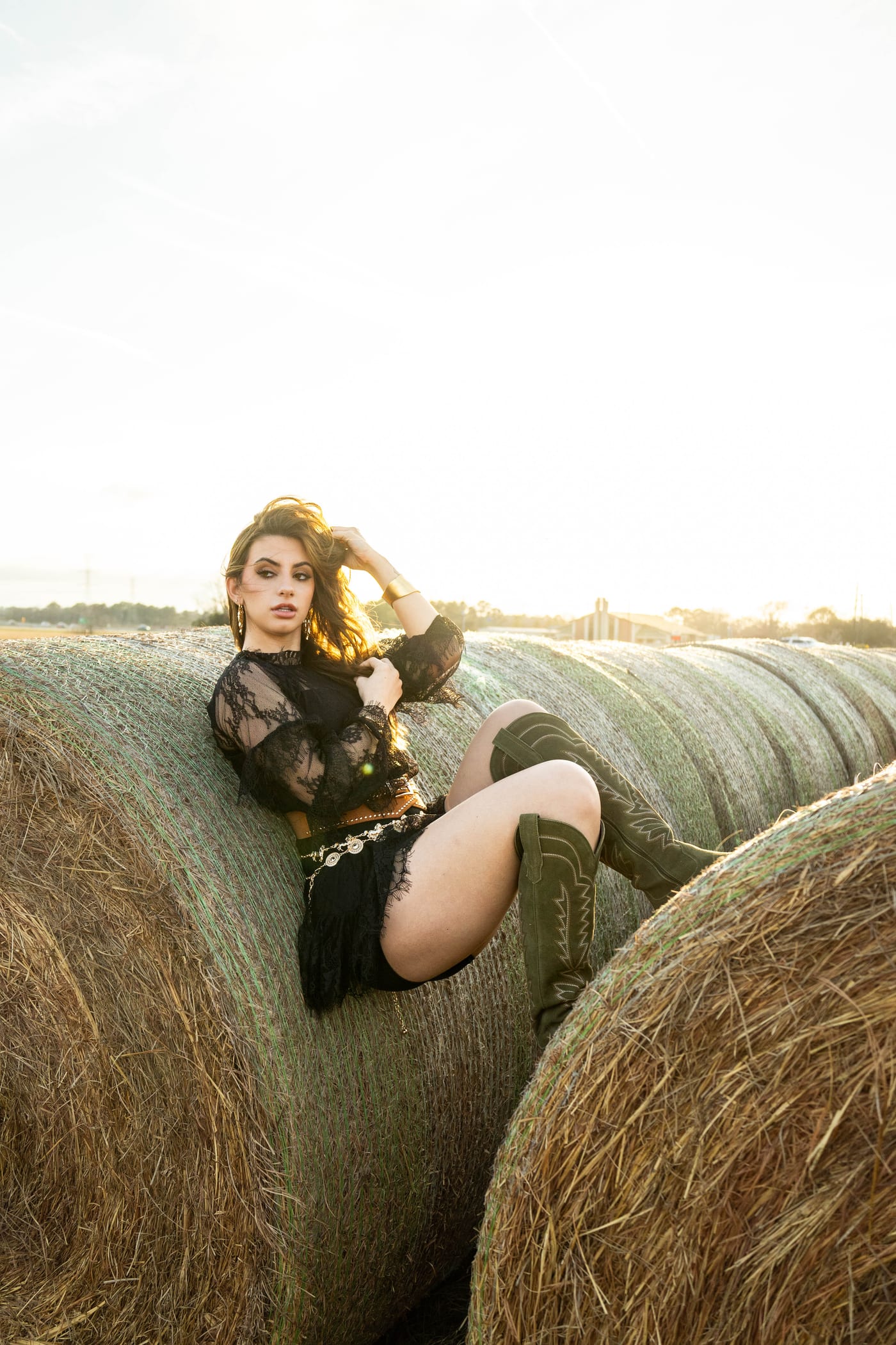 Senior editorial portrait on hay bales at golden hour