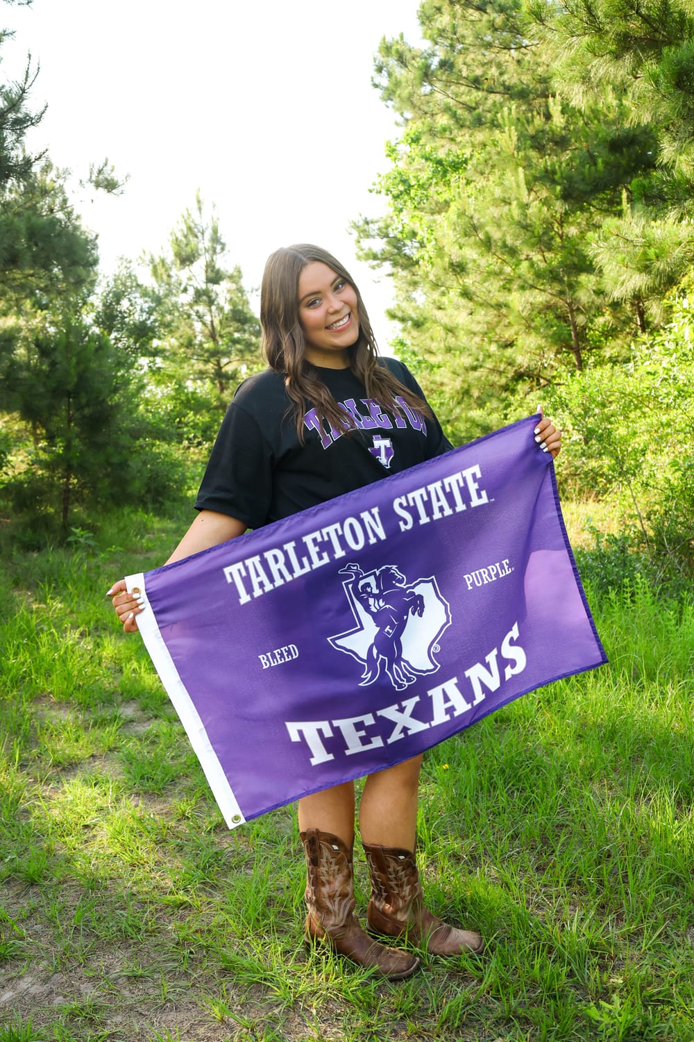 Senior with Tarleton State flag in a clearing